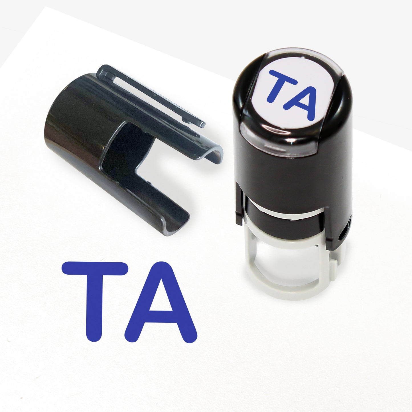 A 10mm self-inking stamp with blue letters 'TA' central to the design. The stamper lid also shows a clip for attaching the stamper to a lanyard.