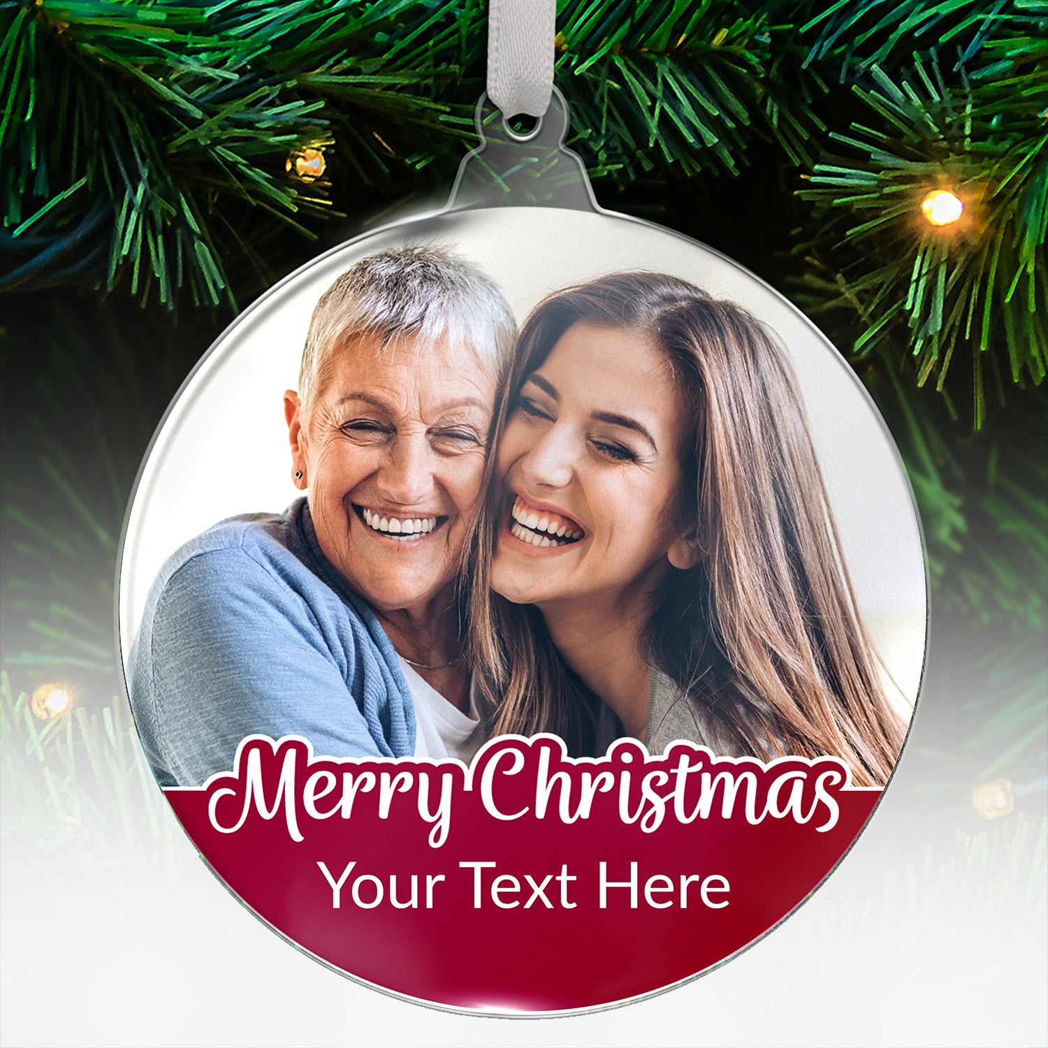 Customisable round acrylic Christmas tree ornament featuring a photo of two smiling women embracing. The bottom section has a red banner with the festive message 'Merry Christmas' and placeholder text 'Your Text Here'. Ornament is hanging from a tree branch with twinkling lights in the background.  There is an overlay saying colour choice on the image.