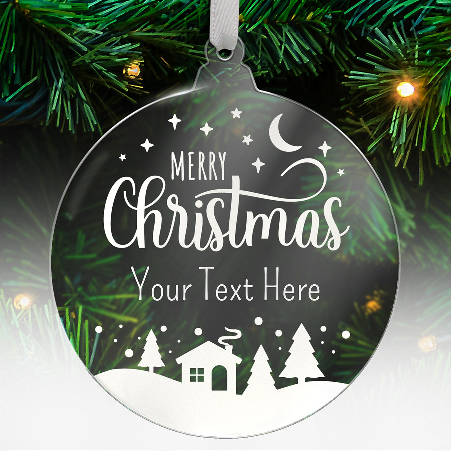 A round, clear acrylic Christmas tree ornament hanging from a white ribbon. The ornament features a festive winter design with the words 'Merry Christmas' in elegant white script, followed by placeholder text 'Your Text Here'. Below, there's a silhouette of a snowy landscape with pine trees, a house with smoke rising from the chimney, and a crescent moon with stars in the sky. The ornament is displayed against a green Christmas tree with lights.
