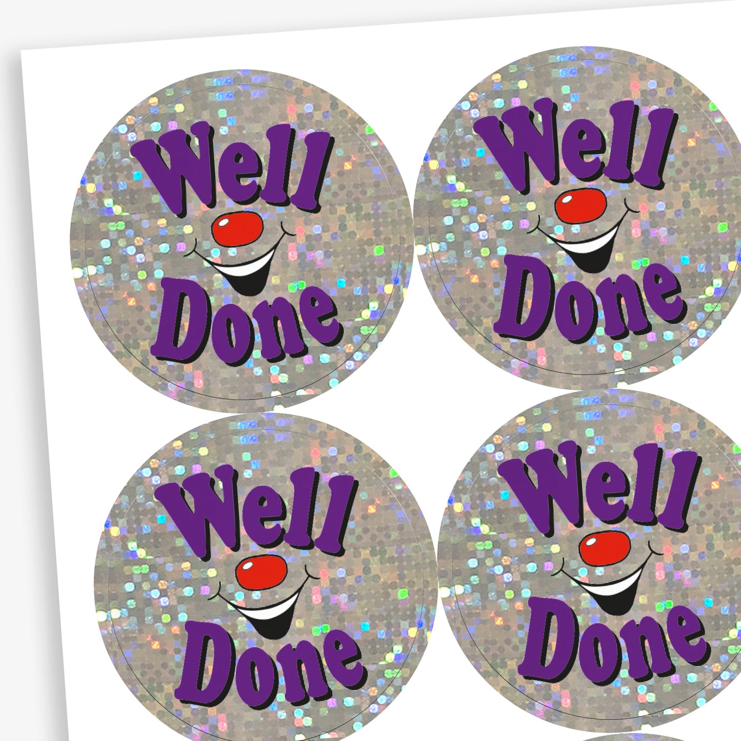 A sheet of holographic circular stickers featuring the text "Well Done" in purple, surrounded by sparkling silver glitter and a smiling clown face.