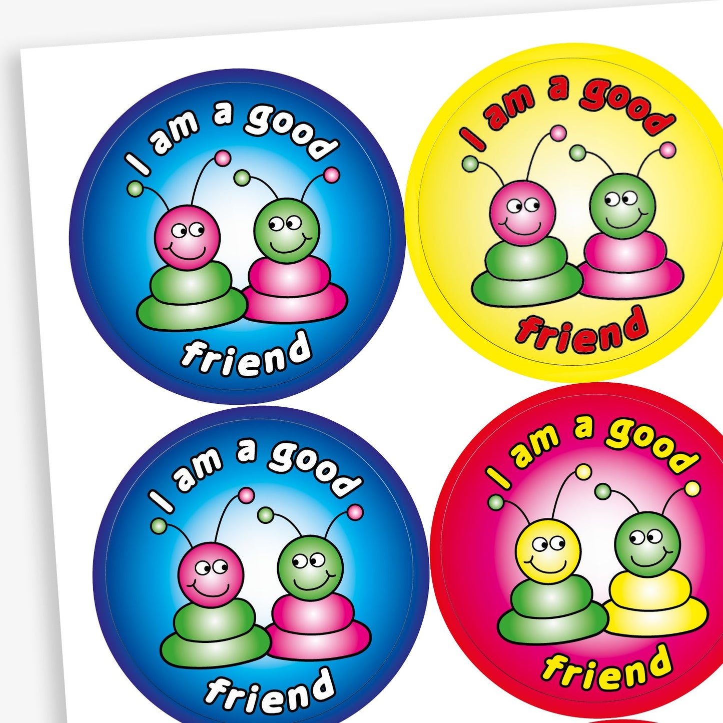 A sheet of round reward stickers in various bright colours, each with the phrase 'I am a good friend' written in bold, playful text. Each sticker features two cartoon alien-like characters with antennae, sitting side by side and smiling. The background colours include red, blue, yellow, and pink gradients, creating a cheerful and encouraging design aimed at promoting positive social behaviour.
