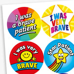 Sheet of colourful circular stickers designed to reward bravery in children. Includes: 'I was a brave patient' written on a rainbow background.  'I WAS VERY BRAVE' inside a yellow star shape. 'I was very BRAVE' with a smiling yellow face on a red and blue background. 'Star Patient' with a smiling yellow star and rainbow trail on a blue background.
