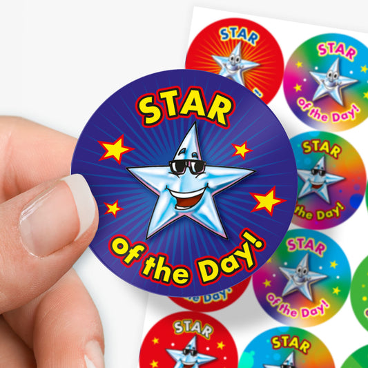 Sheet of round 'Star of the Day' reward stickers featuring smiling cartoon stars with expressive faces. Each sticker has the same message but comes in a variety of vibrant background colours, including green, blue, red, and yellow.