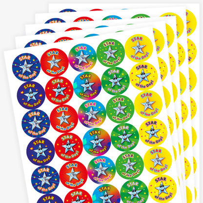 Sheet of round 'Star of the Day' reward stickers featuring smiling cartoon stars with expressive faces. Each sticker has the same message but comes in a variety of vibrant background colours, including green, blue, red, and yellow.
