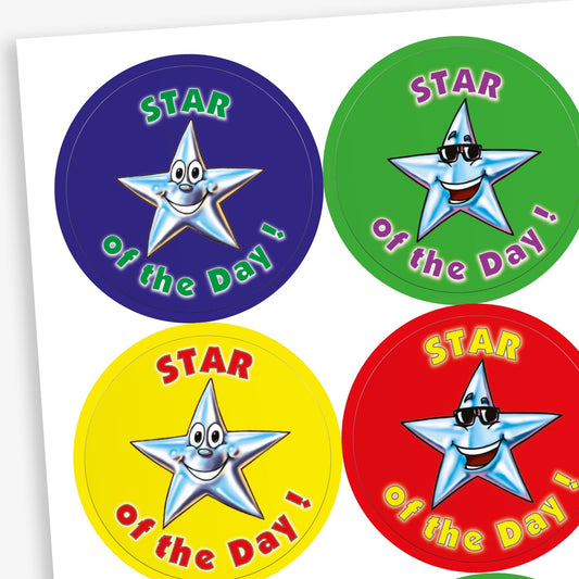 Sheet of round 'Star of the Day' reward stickers featuring smiling cartoon stars with expressive faces. Each sticker has the same message but comes in a variety of vibrant background colours, including green, blue, red, and yellow.