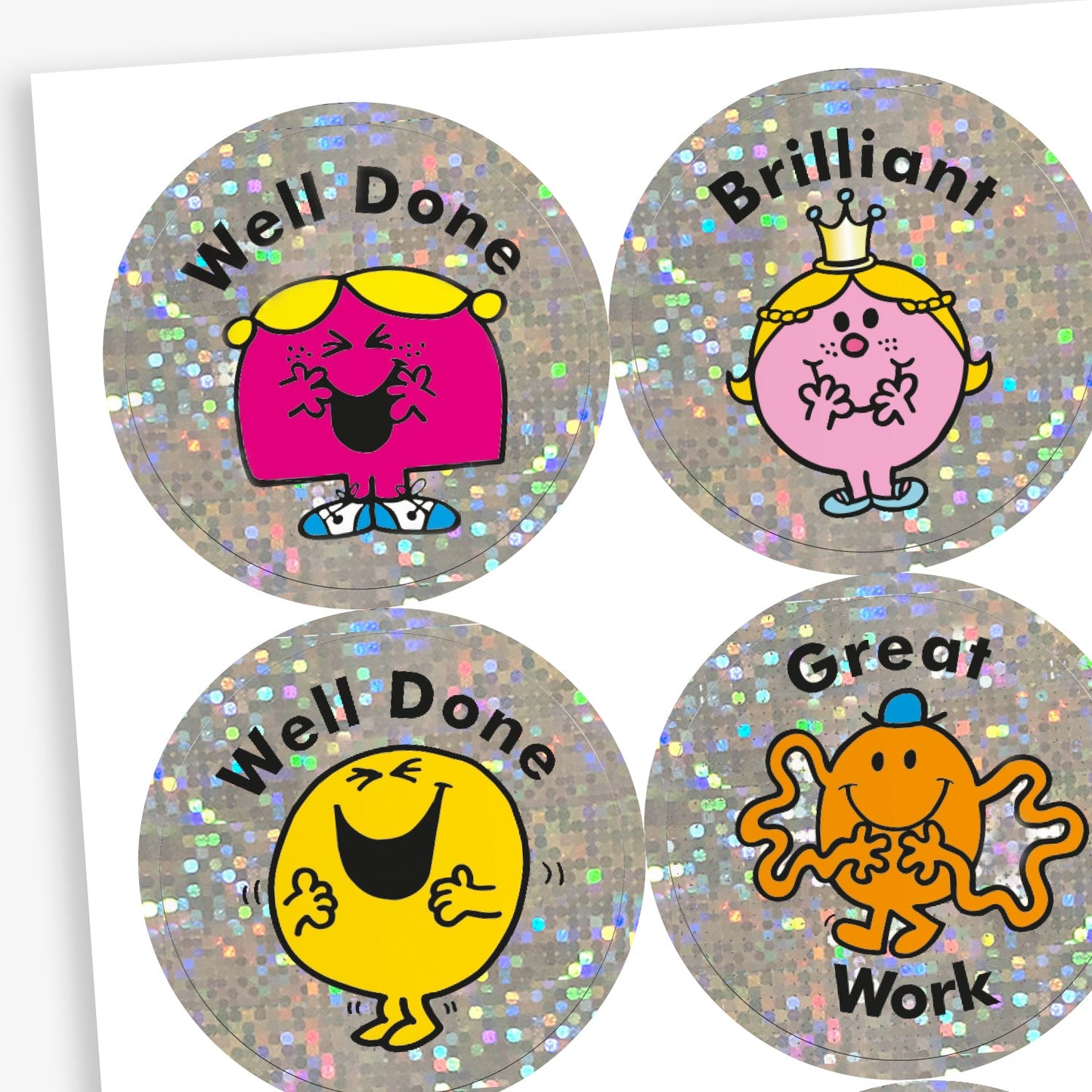 A snapshot of a sheet of holographic circular reward stickers featuring Mr. Men and Little Miss characters on a silver glittery background. Top left: Little Miss Giggles with the text 'Well Done'. Top right: Little Miss Princess with the word 'Brilliant'. Bottom left: Mr. Happy with 'Well Done'. Bottom right: Mr. Tickle with the words 'Great Work'.