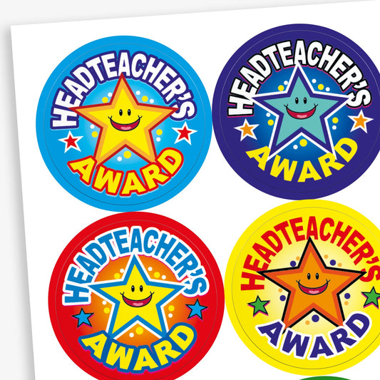 A sheet of colourful circular 'Headteacher’s Award' stickers, each featuring a smiling star with different background colours—blue, purple, red, and yellow. The designs are vibrant and celebratory, with bold text and star accents.