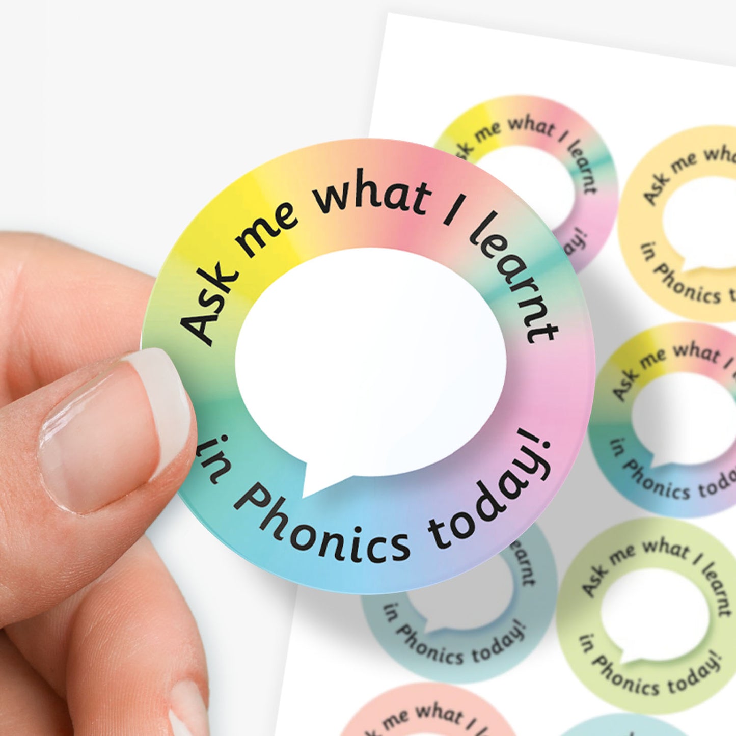 Colorful circular sticker with text 'Ask me what I learnt in Phonics today!' with sticker sheet in the background.