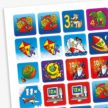 A sheet of colourful multiplication-themed stickers, each representing a times table from 2× to 12×. The stickers feature playful illustrations such as sunflowers for 2×, a dog for 3×, a dinosaur for 4×, kites for 5×, a ship for 6×, a rocket for 7×, a ball for 8×, a green alien for 9×, wizards for 10×, an aeroplane for 11×, and computers for 12×. Each sticker has a vibrant background and cartoon-style imagery.