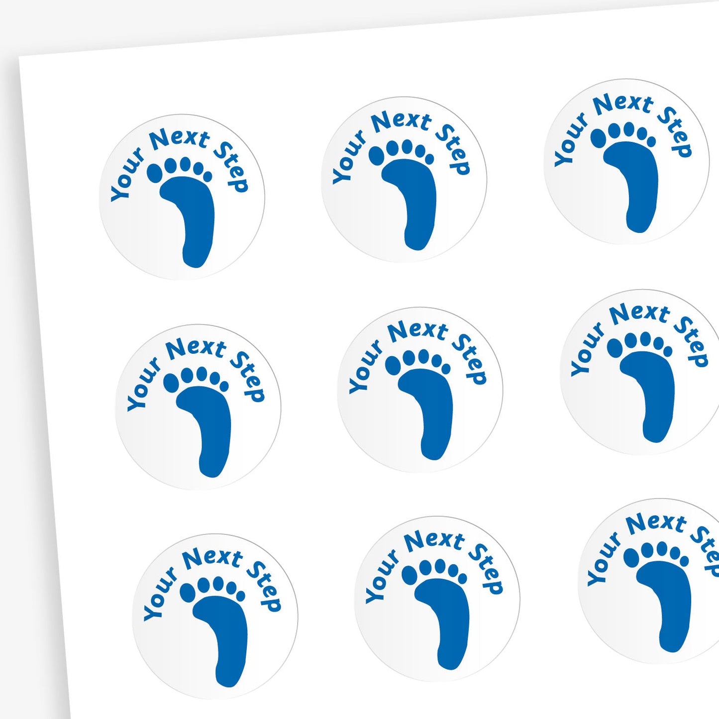 A sheet of white circular stickers featuring 'Your Next Step' in blue above a footprint in blue.