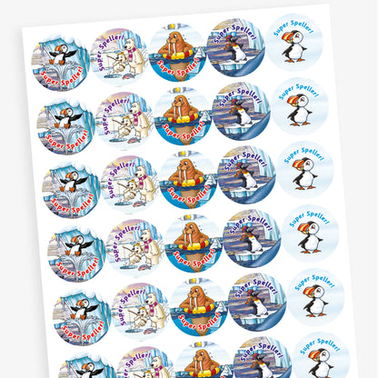 A sheet of circular reward stickers with the phrase 'Super Speller!' in blue or red text. Each sticker features arctic-themed cartoon animals such as puffins, polar bears, and walruses, engaging in playful or reading-related activities against icy, snowy backdrops. The designs are colourful and cheerful, celebrating spelling achievement.
