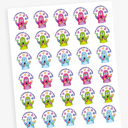 A sheet of circular reward stickers featuring colourful cartoon characters with raised hands juggling numbered circles. The text on each sticker reads 'I've mastered my maths' in bold blue letters. The characters appear in various bright colours including pink, green, and blue, celebrating achievement in mathematics.