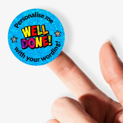 Blue sticker with 'Well Done!' text on a glittery background held by a hand.