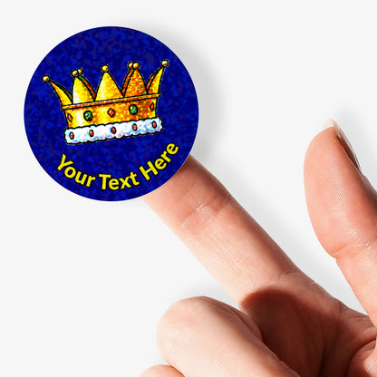 Round blue sticker with a gold crown and customizable text held between fingers.