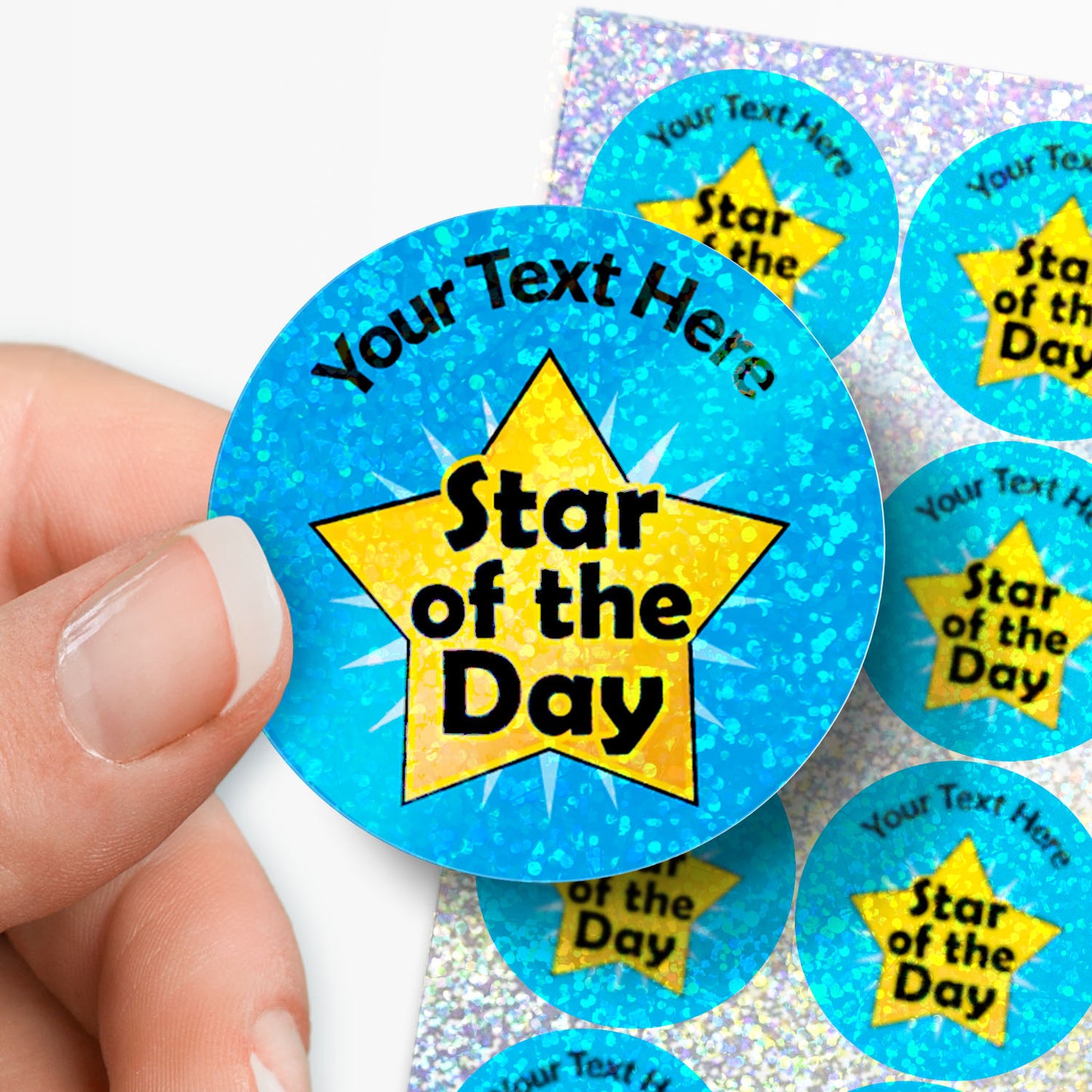 Personalised holographic sticker with 'Star of the Day' design on a blue background held by a hand with sticker sheet in the background.