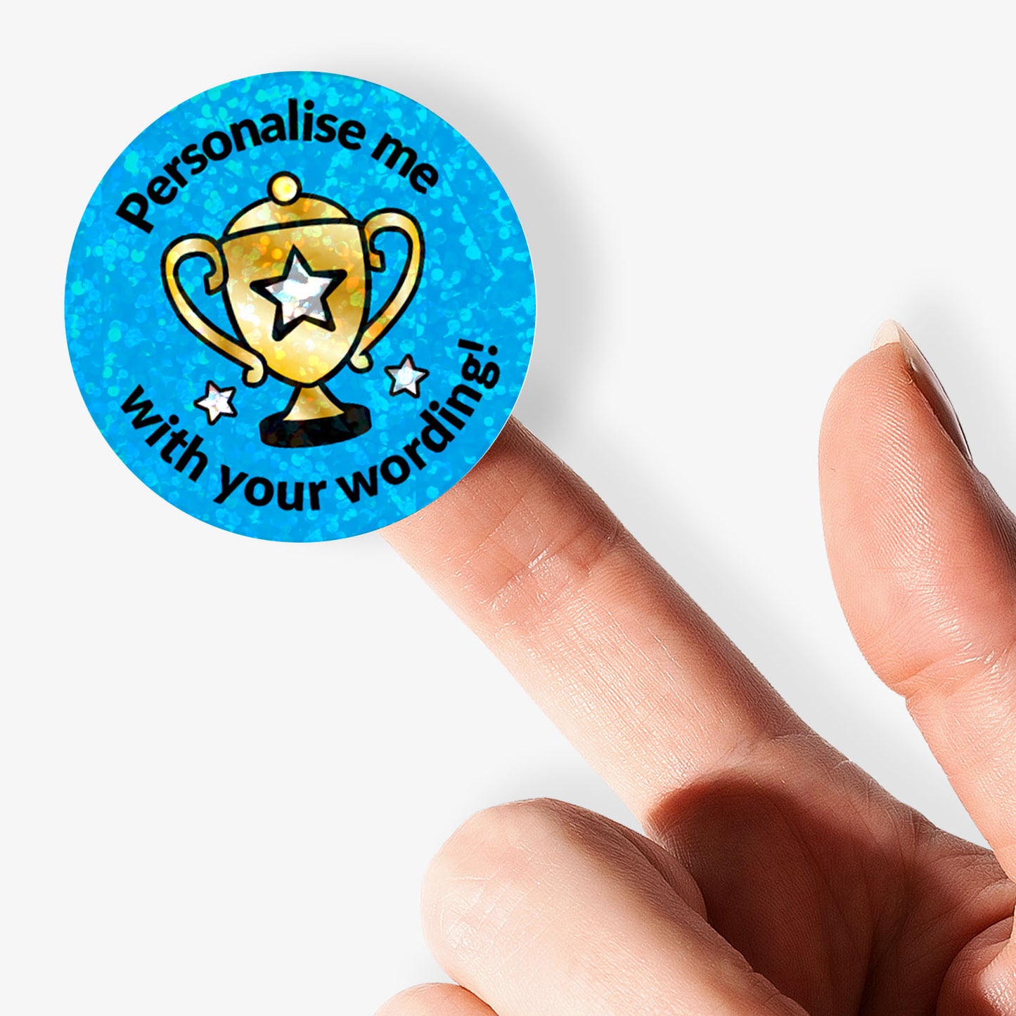 Personalised holographic round sticker with trophy design and text 'Personalise me with your wording' held with finger.