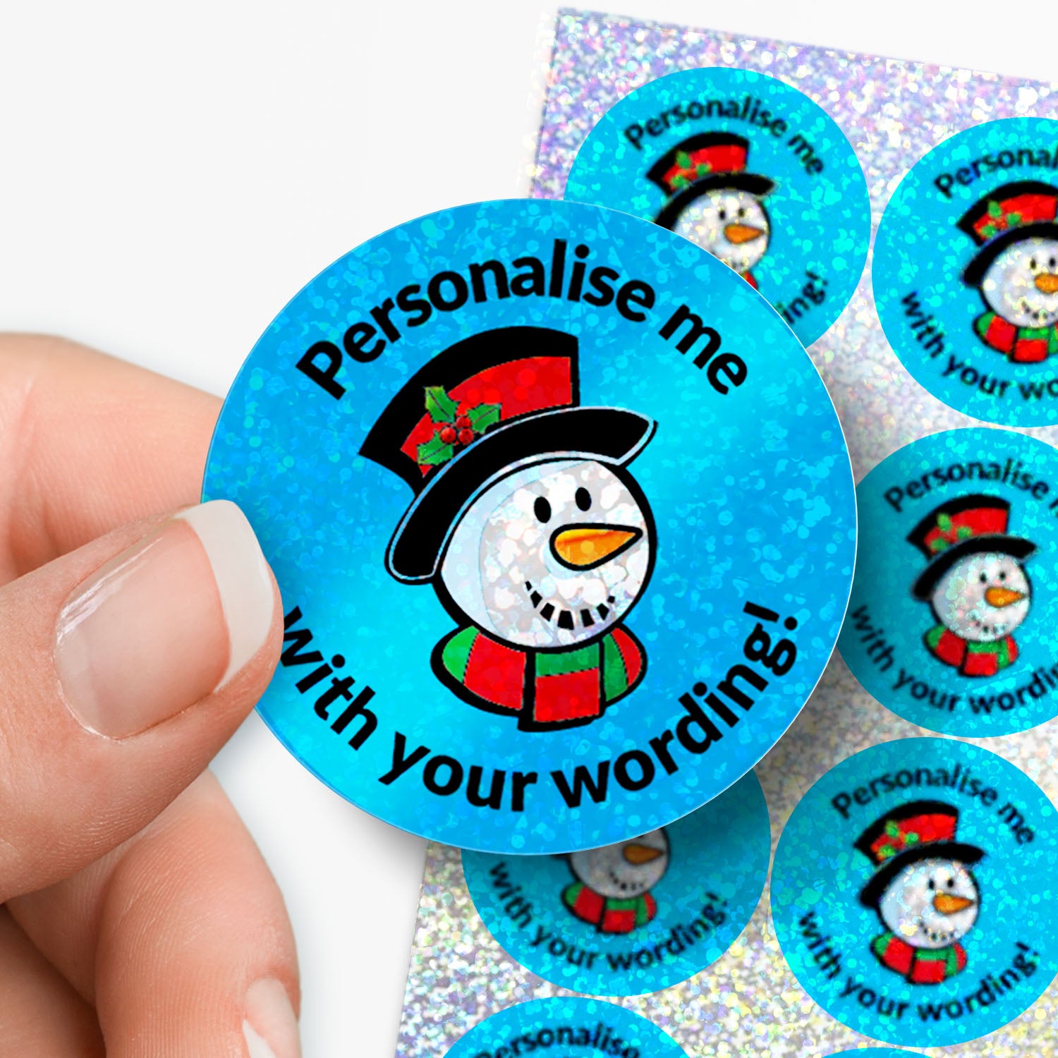 Round blue sticker with snowman design and text 'Personalise me with your wording!' held by a hand.