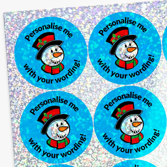 Round blue stickers with snowman design and text on a glittery background