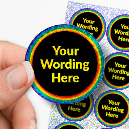 Personalised holographic round stickers with rainbow border and 'Your Wording Here' text, held by a hand.