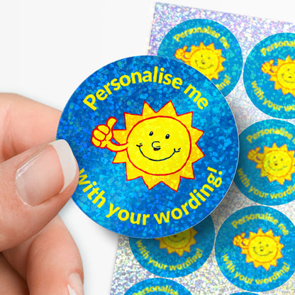 Round blue sticker with sun graphic and text 'Personalise me with your wording!' held by a hand.
