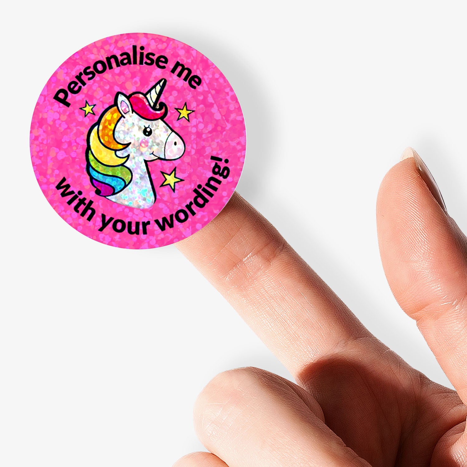 Pink round sticker with a unicorn design and text 'Personalise me with your wording!' held between fingers.