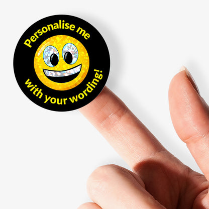 Round sticker with smiley face and text 'Personalise me with your wording!' held by a finger on a white background