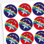 Sheet of 37mm or 25mm round 'Star of the Week' stickers featuring a smiling silver star character set against various vibrant backgrounds, including red, blue, and purple, with rainbow accents; designed to celebrate and motivate pupils for outstanding achievements