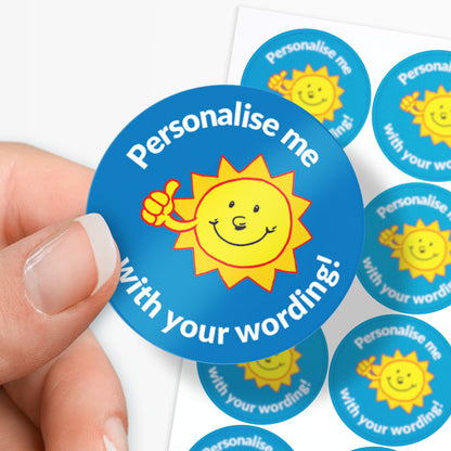 Circular blue sticker with sun graphic and text 'Personalise me with your wording!' held by a hand.