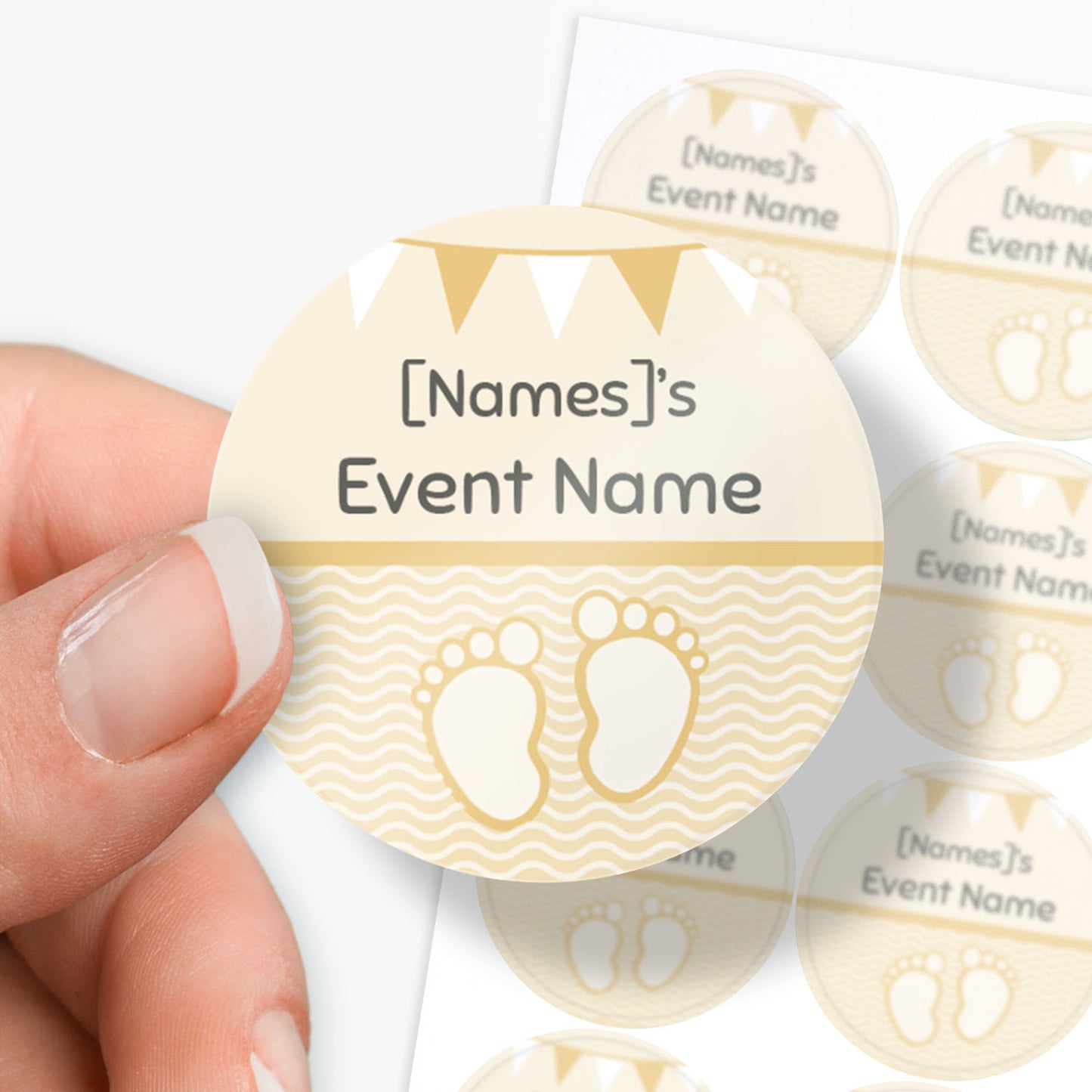 Circular sticker with cartoon baby feet and text being held by a finger and thumb