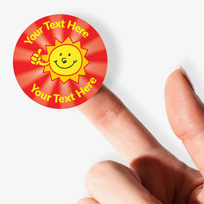 Personalizable sticker with a sun design and text space held between fingers on a white background