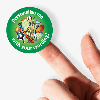 Round green sticker with sports icons and text 'Personalise me with your wording!' held between fingers.