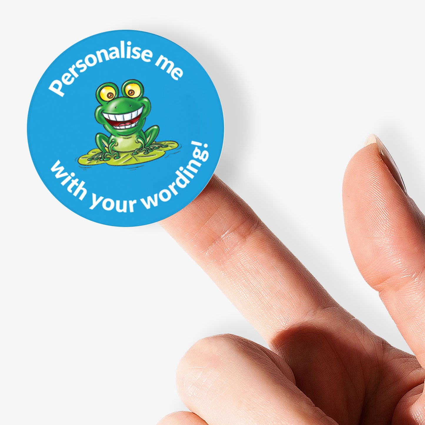 Round blue sticker with a frog graphic and text on a finger.