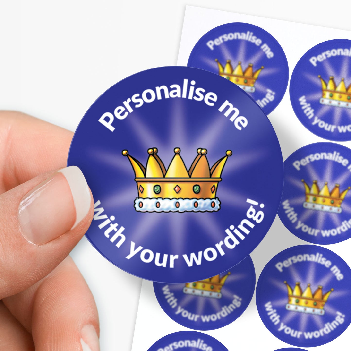 Circular blue sticker with a crown and text 'Personalise me with your wording!' held by a hand.