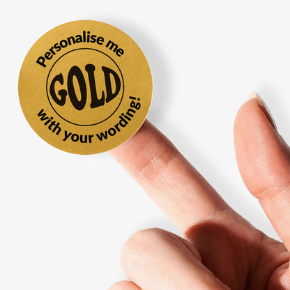 Gold circular sticker with 'Personalise me with your wording!' text held on finger.
