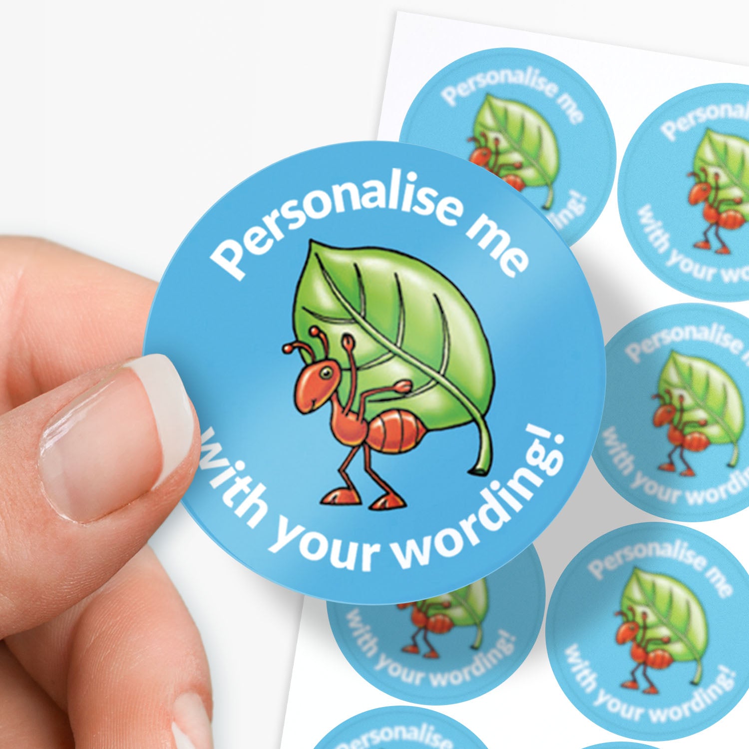 Circular blue sticker with cartoon ant and leaf design, held by a hand.