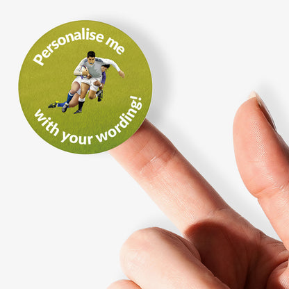 Round green sticker with rugby player graphic and text 'Personalise me with your wording!' held by a finger.