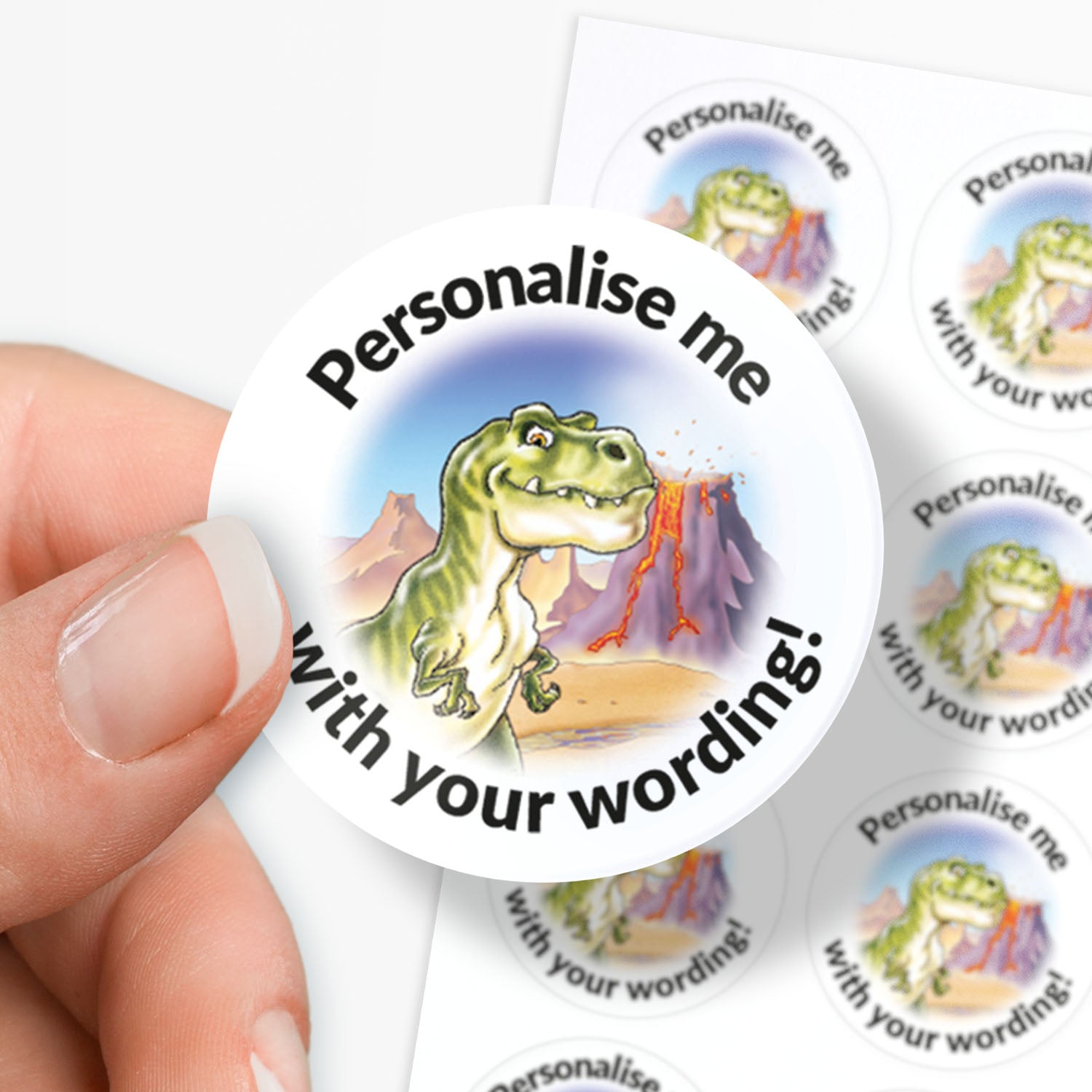 Round customizable sticker with a dinosaur illustration and text 'Personalise me with your wording!' held by a hand.