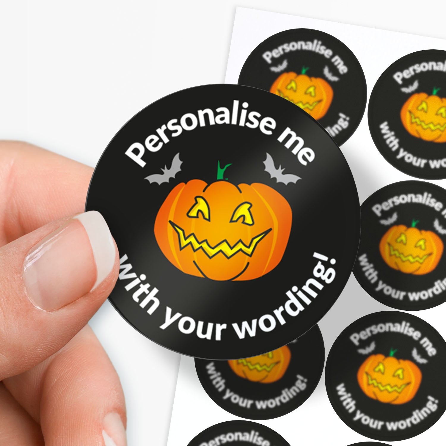 Halloween-themed sticker with a pumpkin face and text 'Personalise me with your wording!' held by a hand.