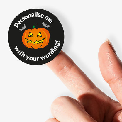 Halloween-themed sticker with a pumpkin and text 'Personalise me with your wording!' held by a finger.