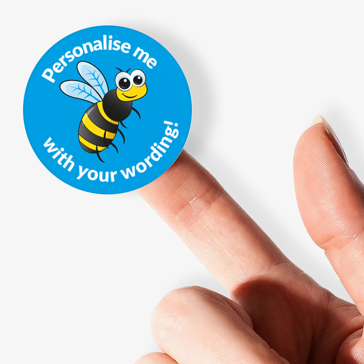 Round blue sticker with a bee graphic and text on a finger against a white background