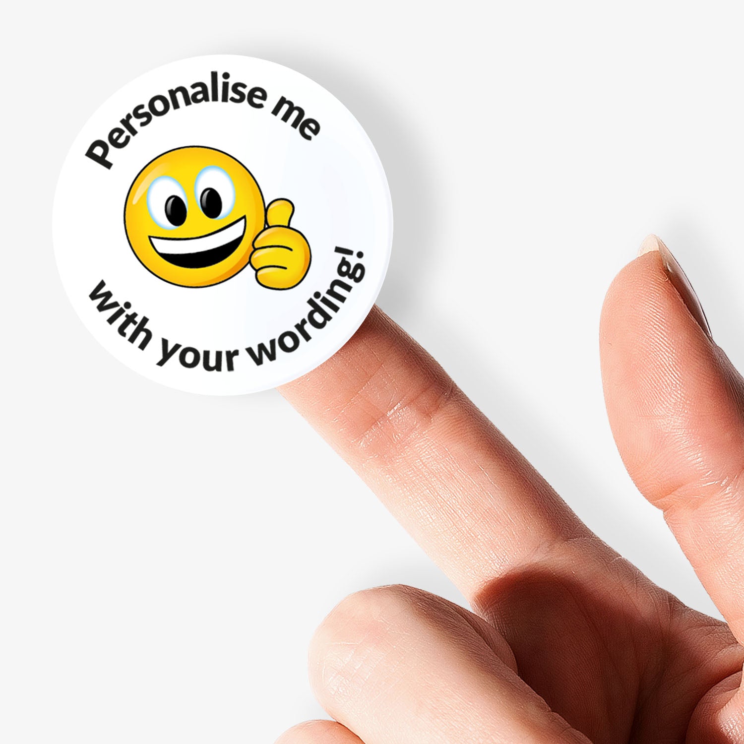 Circular sticker with smiley face and text 'Personalise me with your wording!' held by a finger on a white background