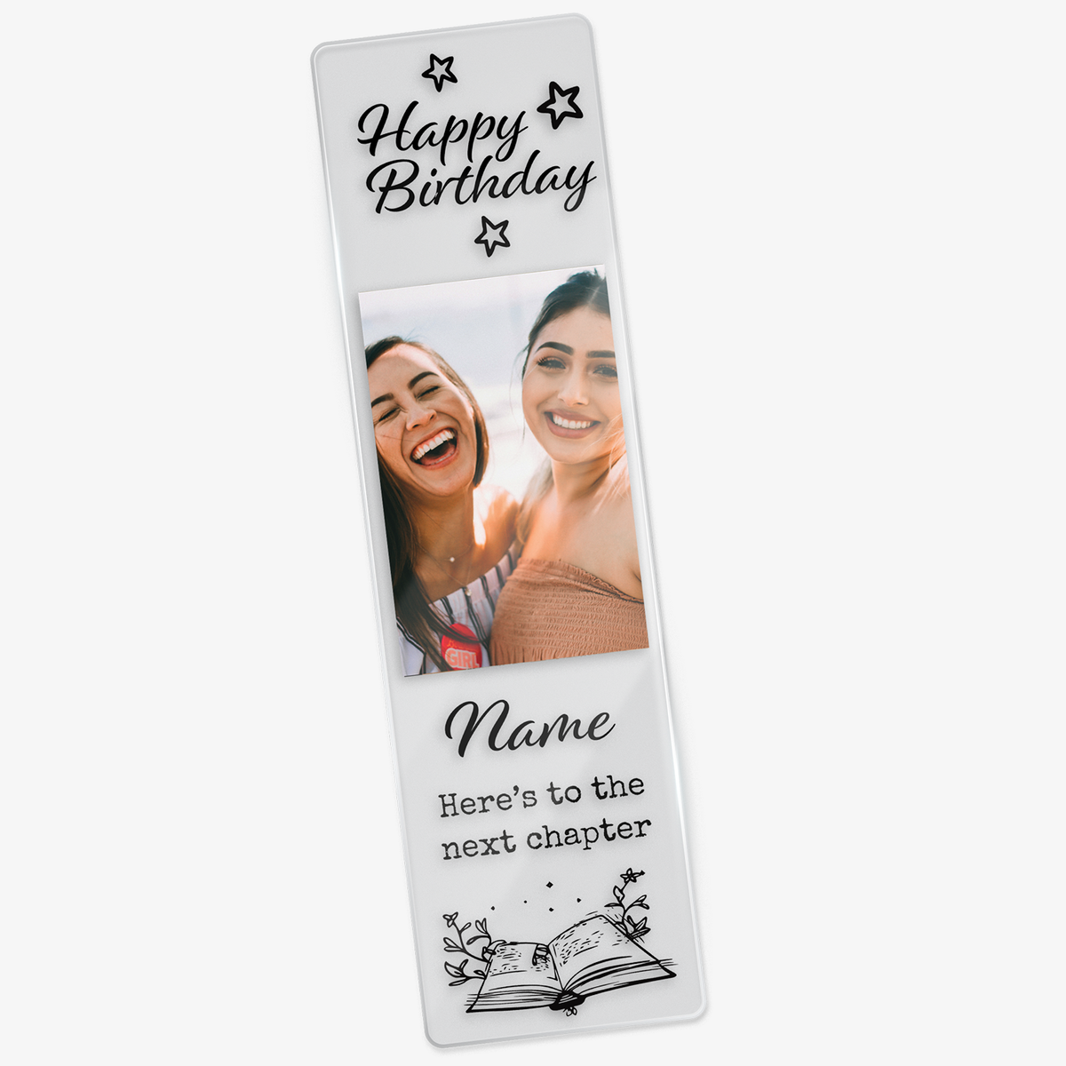 Clear acrylic bookmark featuring the phrase 'Happy Birthday' at the top, a photo of two friends, and the words 'Name' 'here's to the next chapter' above an illustrated open book with magical elements.