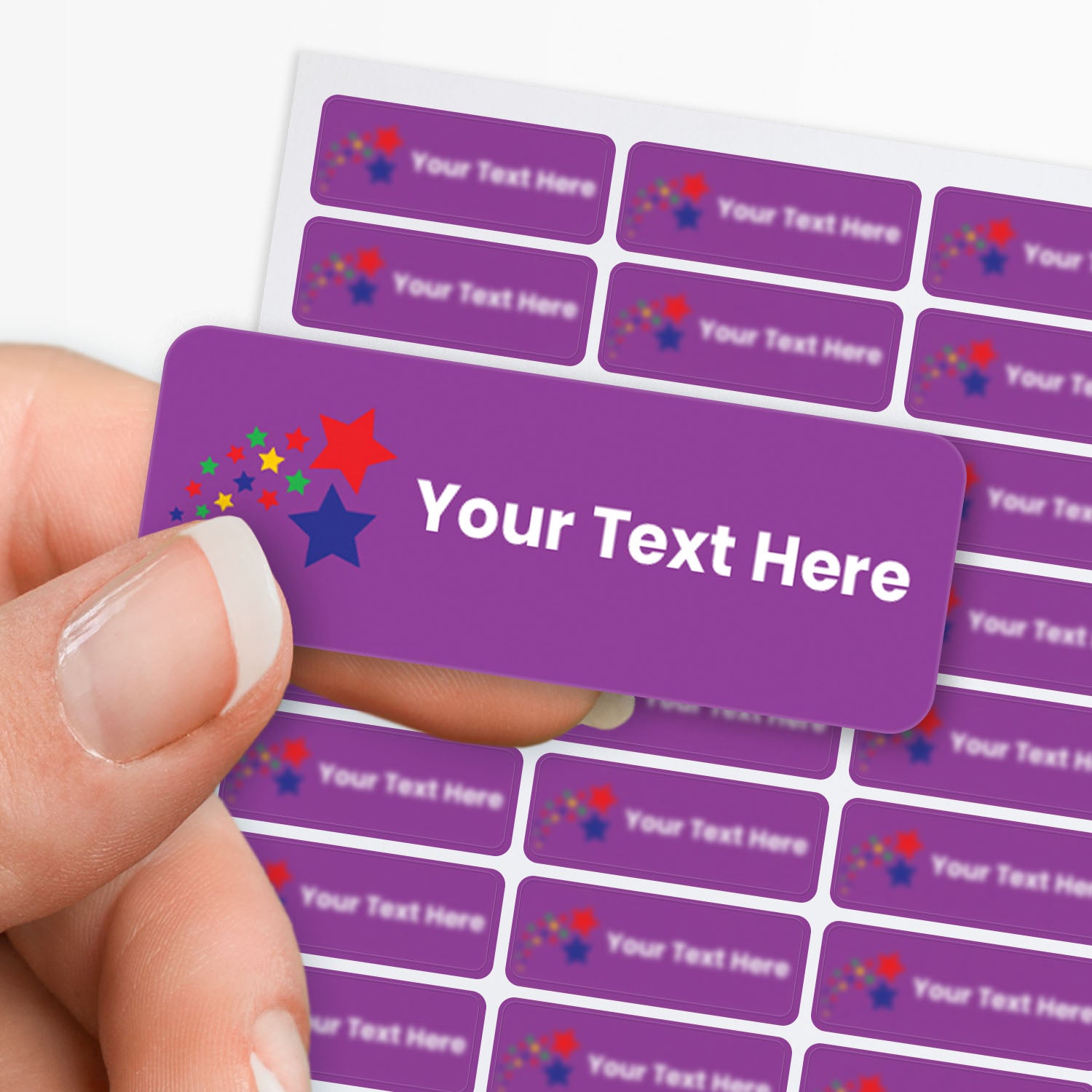 Purple stickers with white text and a shoting stars icon held by a hand with a sticker sheet in the background