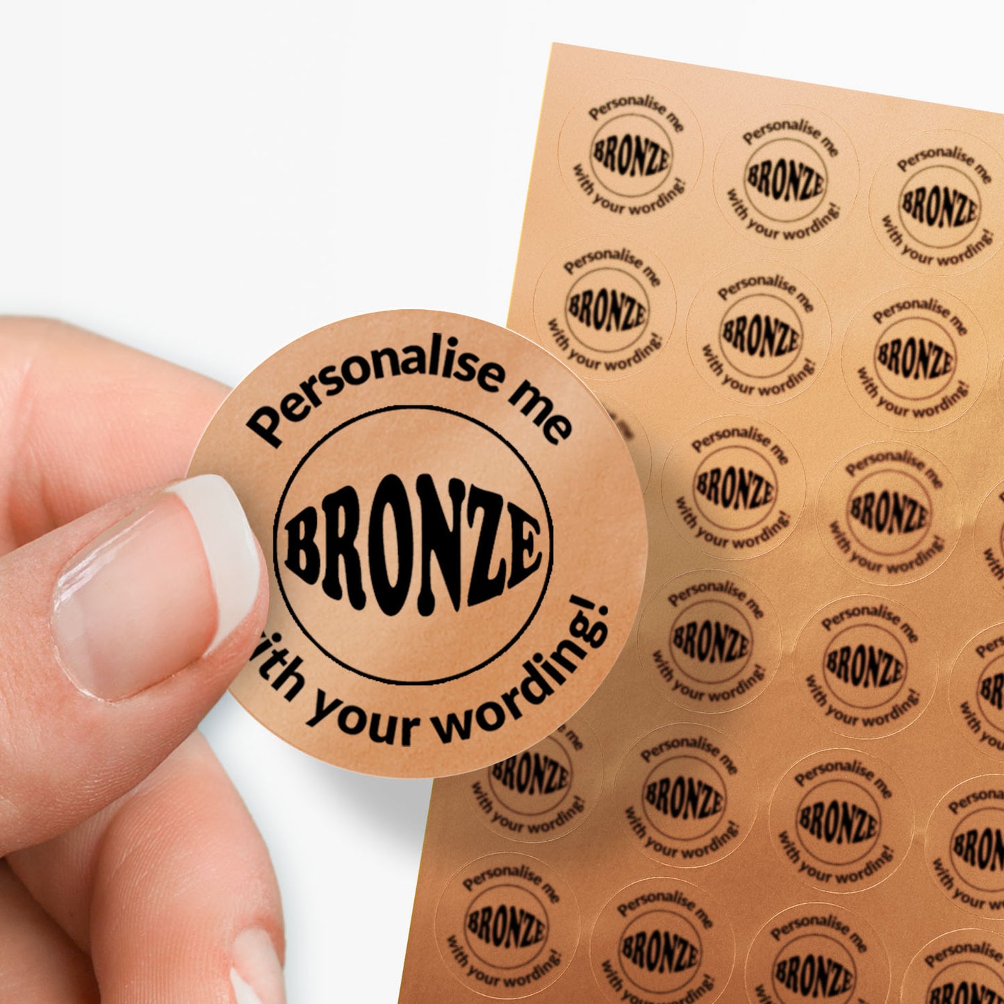 Sheet of bronze stickers with a black bronze word in the middle and text. single sticker held between finger and thumb