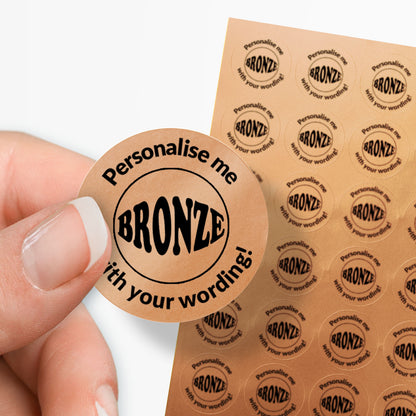 Sheet of bronze stickers with a black bronze word in the middle and text. single sticker held between finger and thumb