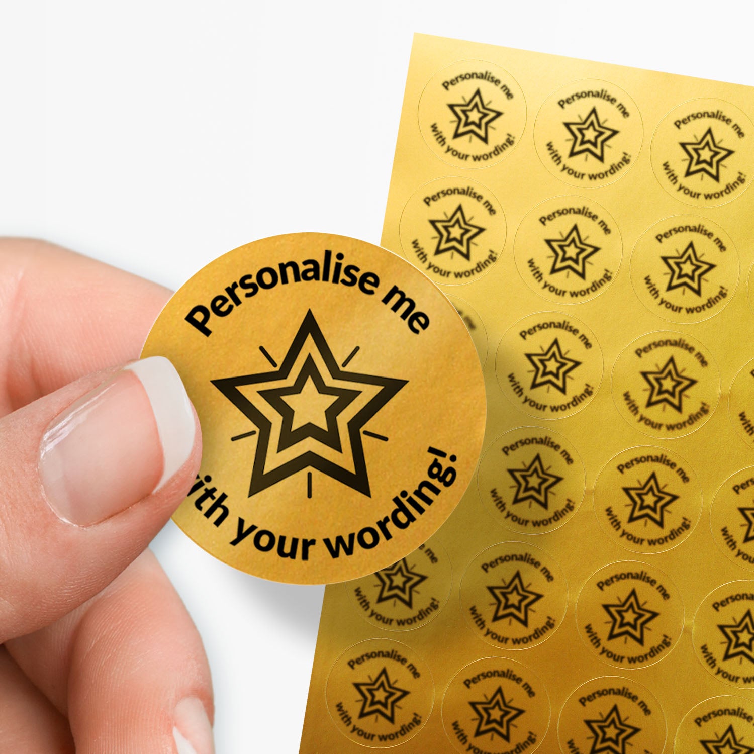Sheet of gold stickers with a black star in the middle and text. Single sticker held between finger and thumb