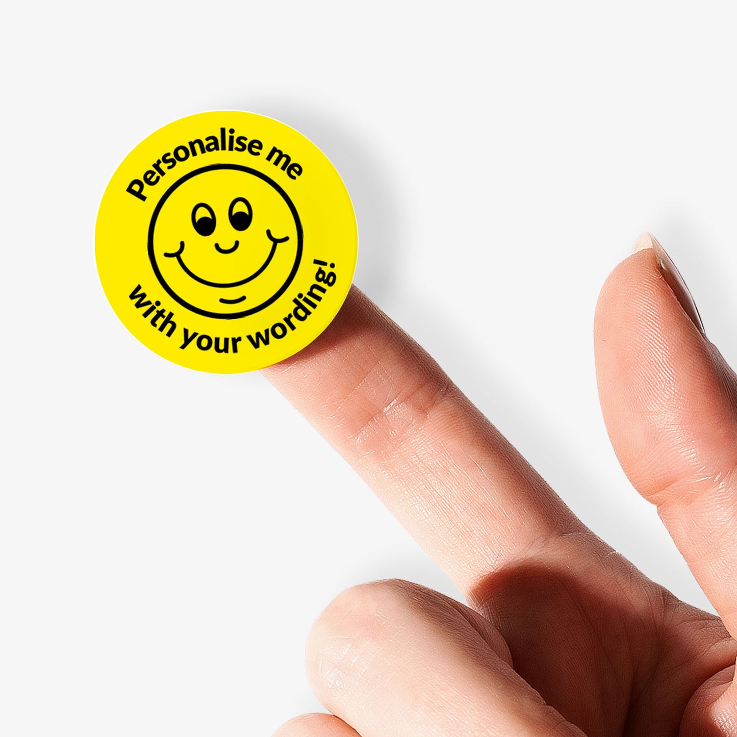 One circular stickers with a smiley face and text on a white background held 
by finger