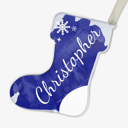 Personalised Christmas stocking-shaped acrylic decoration with the name 'Christopher' written in white script on a blue background, featuring a snowflake design, placed on a white surface.