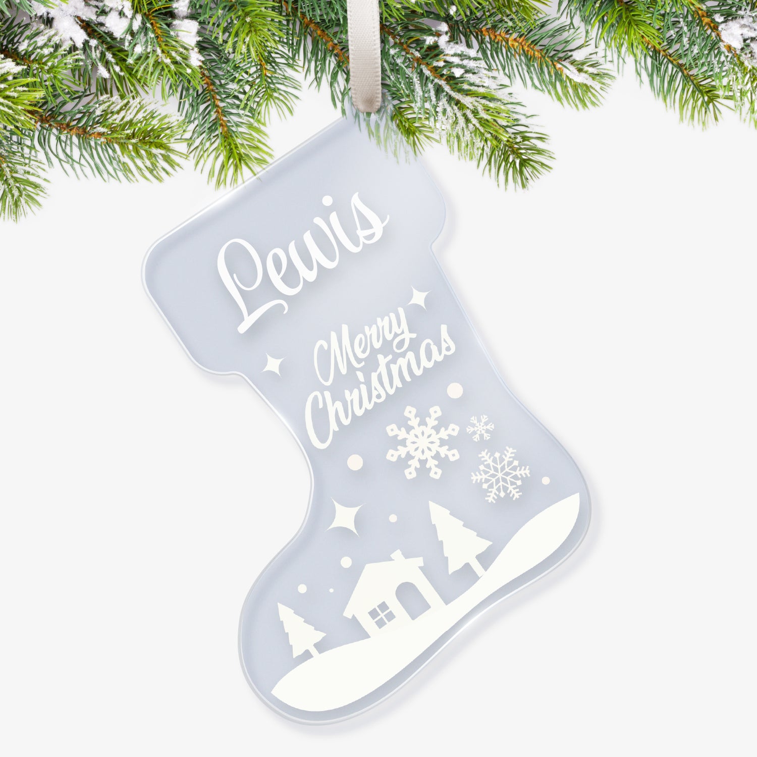 Clear acrylic Christmas stocking-shaped tree ornament decorated with a white winterscene of snow falling on a house with trees, featuring a space at the top for a customisation saying 'Lewis' in white script, with further script writing below in white saying 'Merry Christmas' hanging on a Christmas tree.