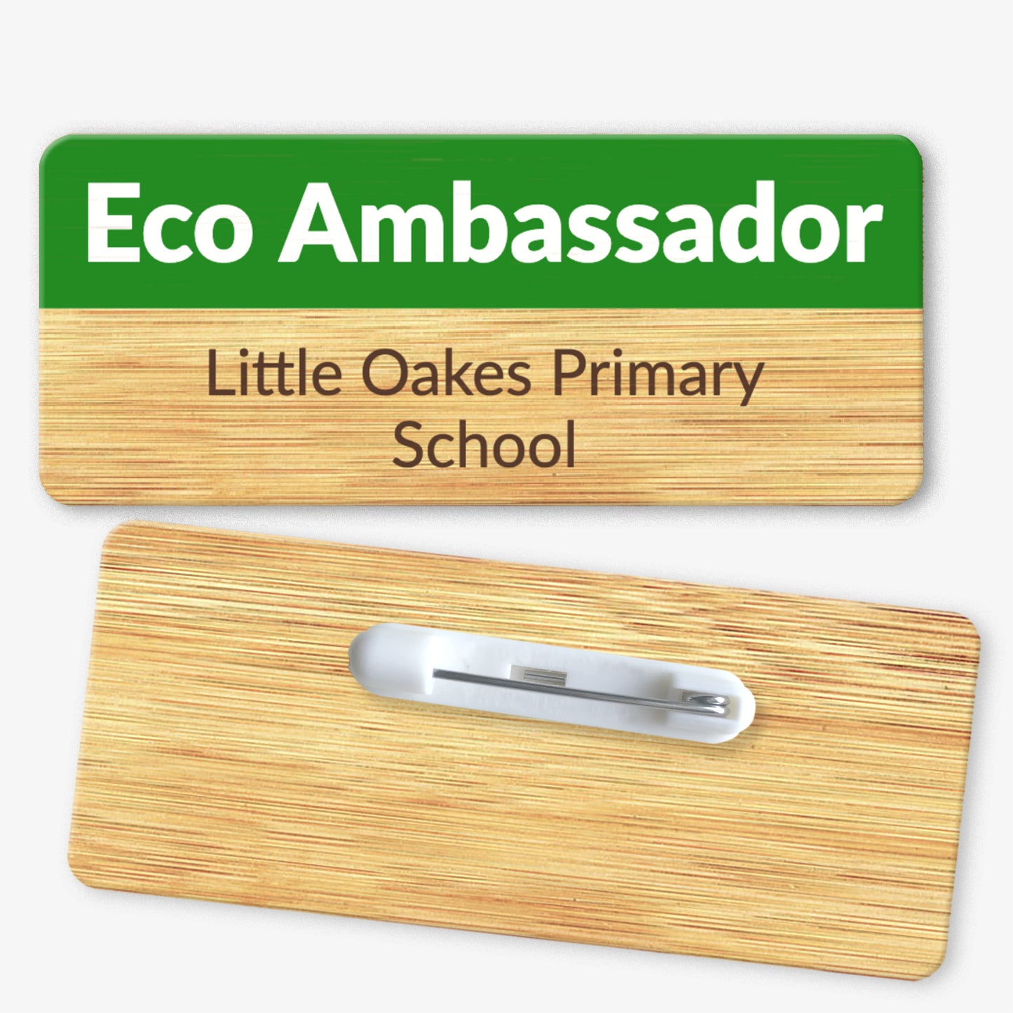 A rectangular bamboo name badge with a natural background and a green top section. The text reads 'Eco Ambassador' in bold white letters on the green part, and 'Little Oakes Primary School' in black below. The reverse side of the badge is also shown, featuring a metal safety pin fastening for attachment.